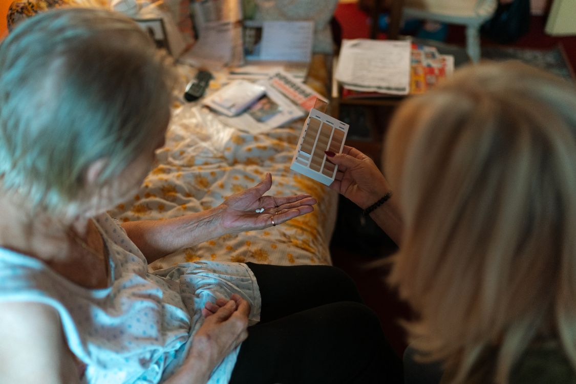 Care professional helping an older adult organize medication at home